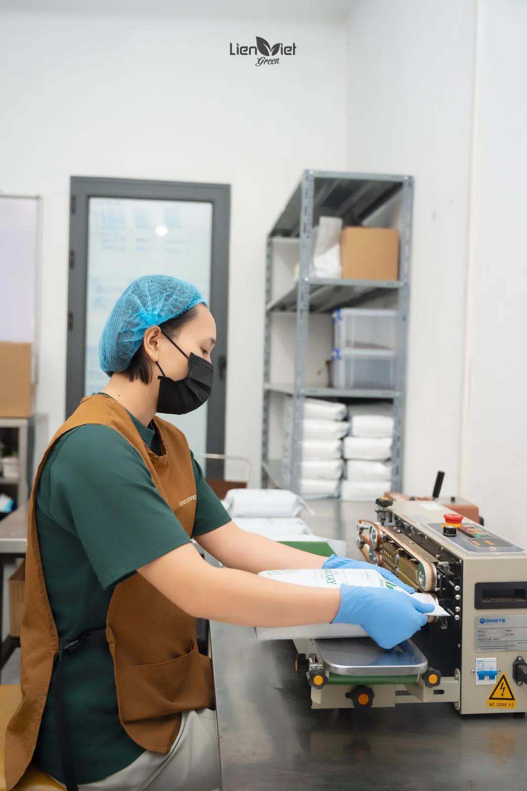 Nhân viên hàn miệng túi cà phê trong phòng đóng gói của xưởng